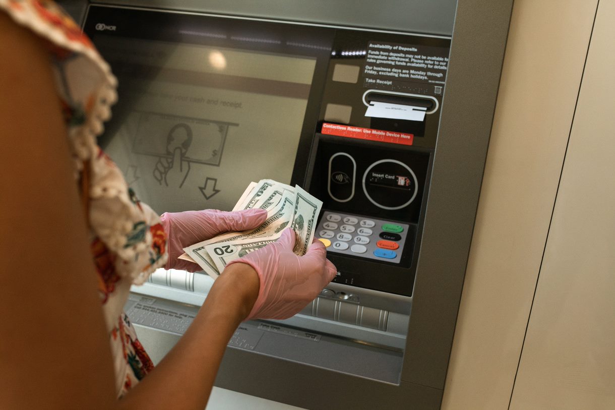 Image of a woman counting money in front of an ATM